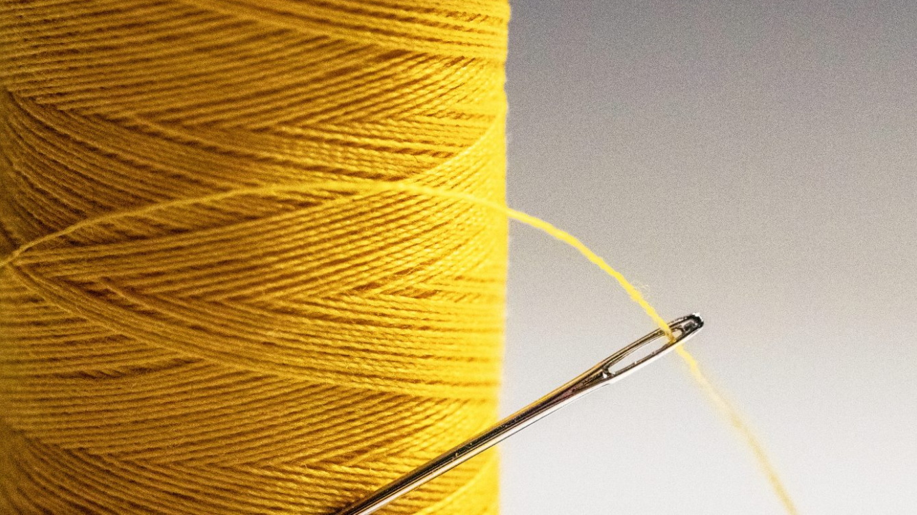 Bobina de hijo amarillo con una aguja enhebrada