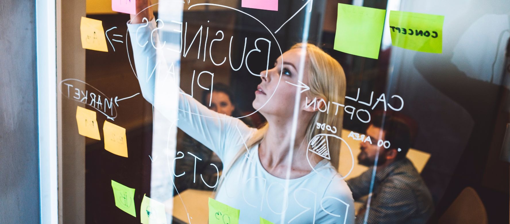 Mujer que pone post it en un cristal