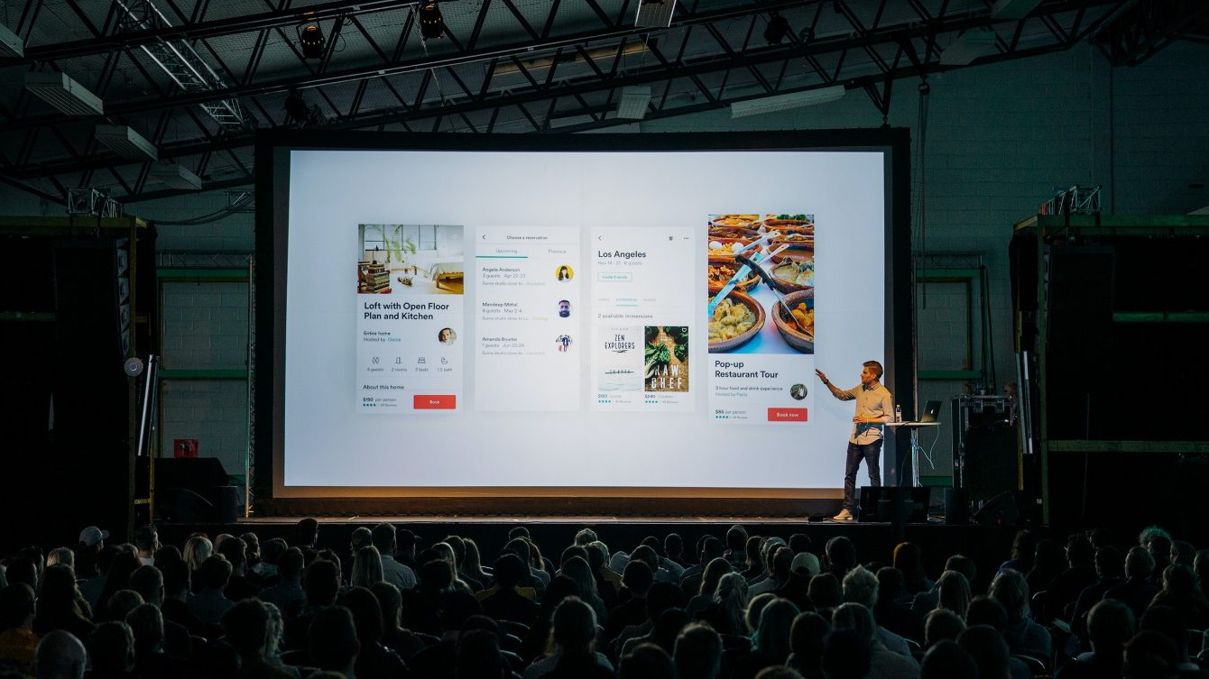 Un hombre explica su proyecto ante un auditorio oscuro