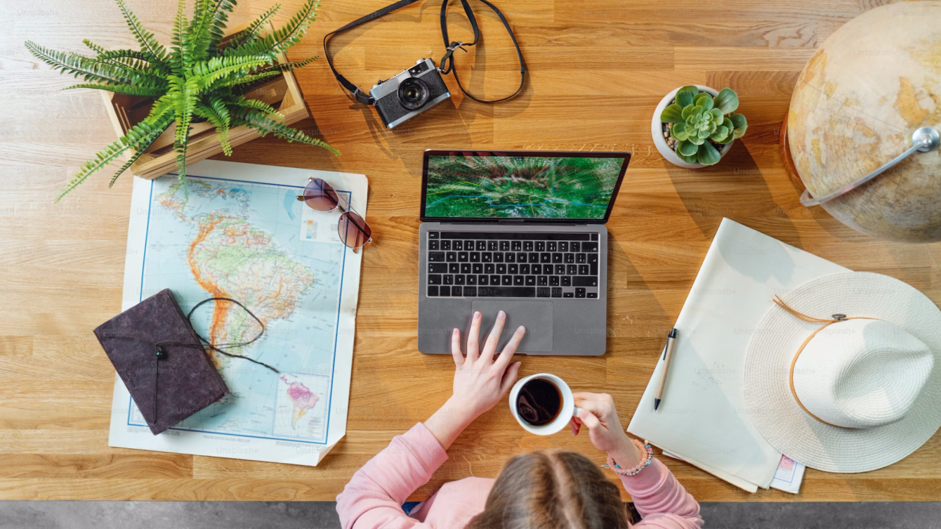 Una mujer toma una taza de café usando un ordenador portátil y está planeando un viaje