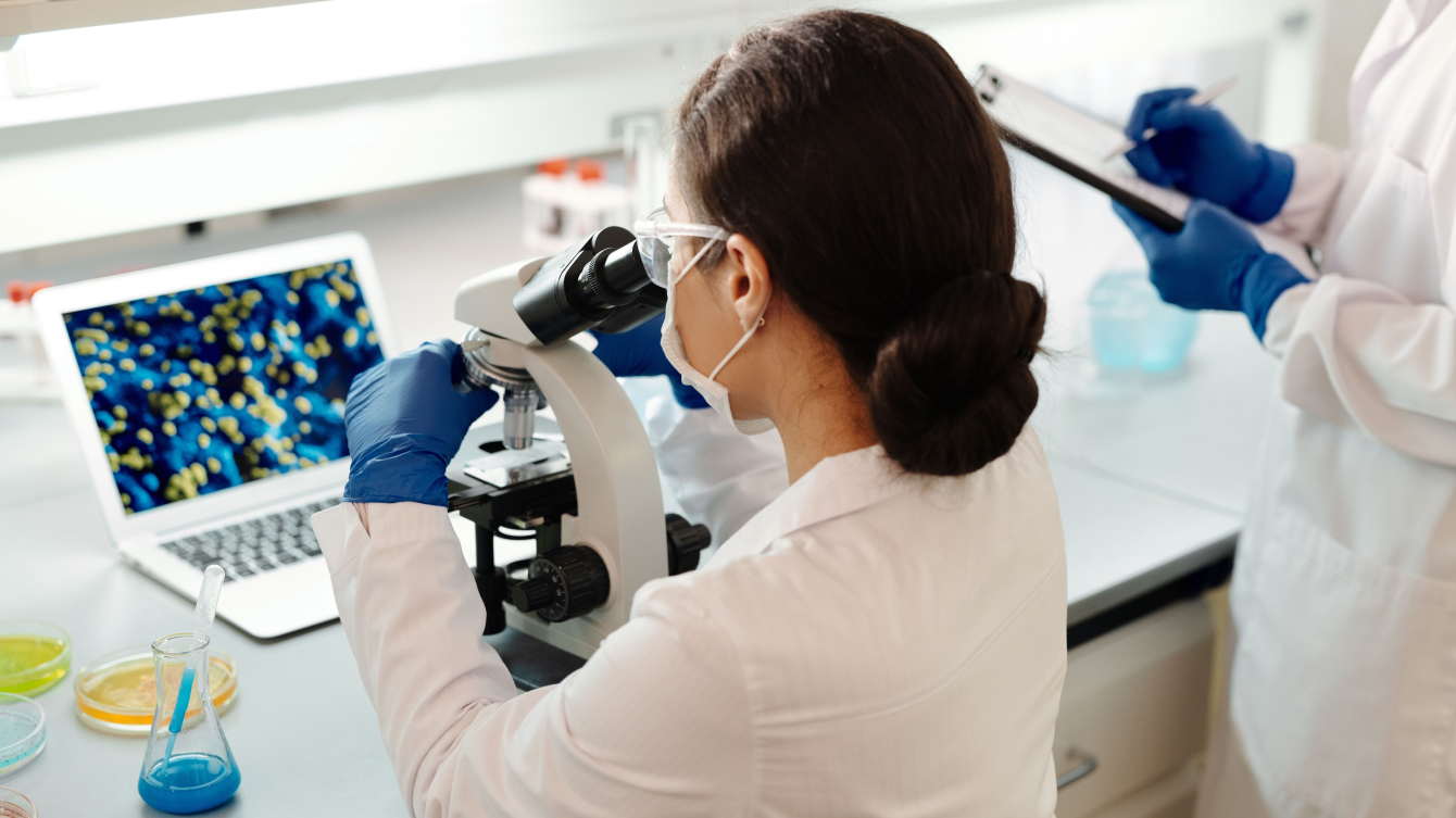 Mujer mirando por un microscopio