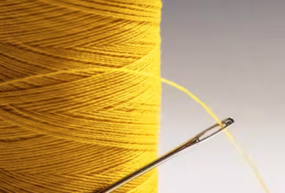 Bobina de hijo amarillo con una aguja enhebrada