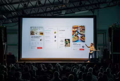 Un hombre explica su proyecto ante un auditorio oscuro