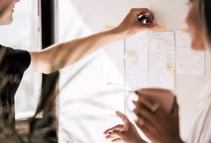 Un hombre y una mujer colocan folios en una pared 